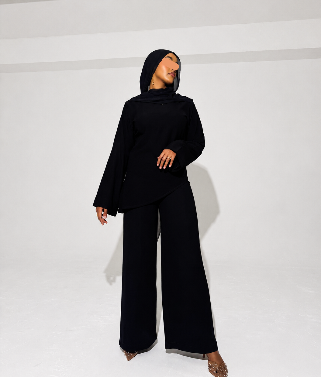 Model wearing a black 2 piece set outfit with asymmetrical top 